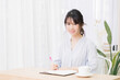 © garage38 - 部屋でノートにメモを書く若い女性