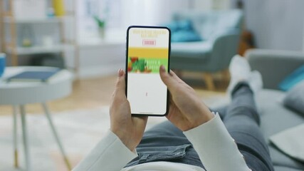 Wall Mural - Woman Lying on Couch Uses Touch Screen Mobile Smartphone Browsing through Online Food Delivery Market, Choosing Through Vegetables Section, Fresh Goods. Internet Store Software with Food to Order