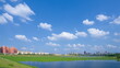 City buildings and lake view in the park under blue sky and white clouds