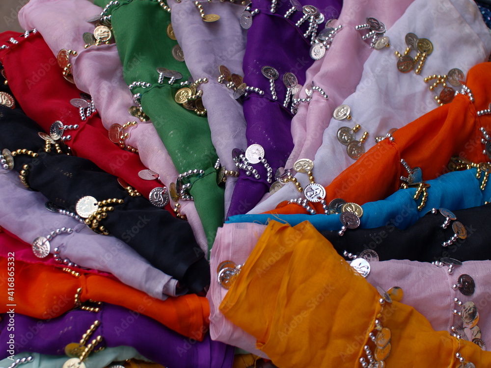 Arabian scarfs in the Market. Colorful fabrics interlaced with jewellery displayed in a circle.