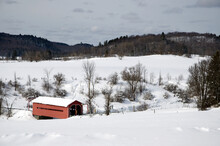 Red Covered Bridge Surrounded By Snow And Mountains In The Background