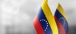 Small national flags of the Venezuela on a light blurry background