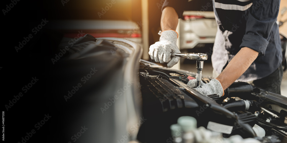 Automobile mechanic repairman hands repairing a car engine automotive workshop with a wrench, car service and maintenance,Repair service. - obrazy, fototapety, plakaty 