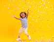 Leinwandbild Motiv Excited African American kid jumping and catching confetti in studio