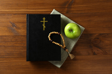 Wall Mural - Bible, rosary beads and apple on wooden table, flat lay. Lent season