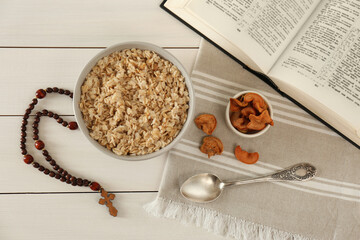 Wall Mural - Rosary beads, oatmeal porridge, dried apples and Bible on white wooden table, flat lay. Lent season