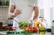© My Ocean studio - Close up photo of young male hands is preparing wonderful fresh vegan salad in the kitchen at home
