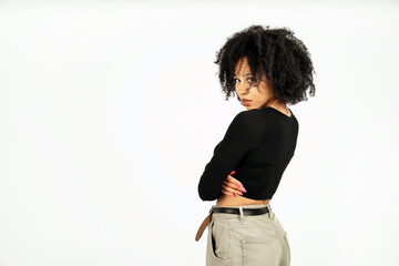 a curly-haired brunette in a black short jacket stands with her back to me. copy space. a woman of Afro appearance poses in a photo studio on a white background.