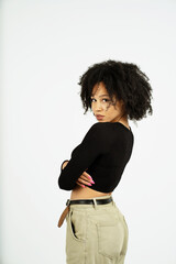 Wall Mural - a woman of Afro appearance poses in a photo studio on a white background. looking at the camera, she crossed her arms in a black short jacket. copy space