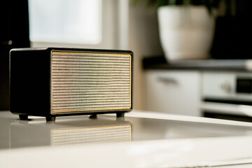 A vintage radio sits on a white table in the kitchen.Stylish music FM wave receiver. Receives the melody via bluetooth channel 5G communication. Cheerful music plays loudly. Copy space.