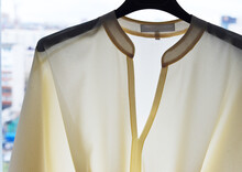 A Blouse With A Light In The Window Hangs On A Hanger. The Seams Show Through.