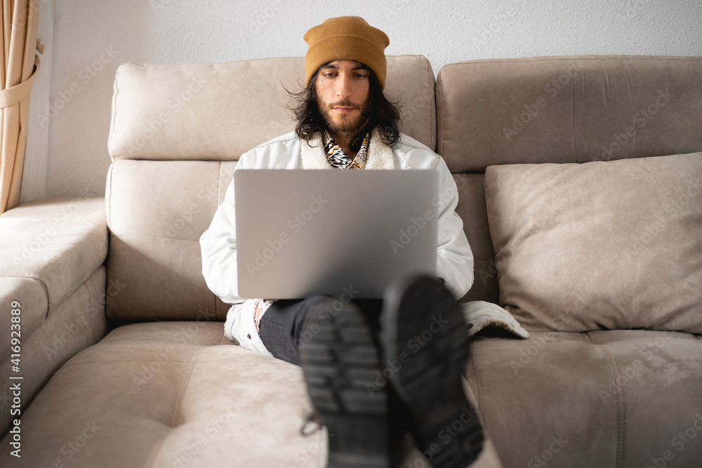 Hombre Joven Con El Pelo Largo Y Un Gorro, Cazadora Vaquera, Camisa,  Pantalón Negro Y Botas, Usando Su Ordenador Portátil Gris De Metal Computer  Wall Mural | Comput-Alex Visualnue