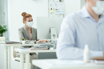 Poster - Young elegant creative designer in protective mask looking at computer screen