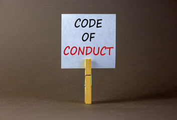 Code of conduct symbol. White paper with words 'Code of conduct', clip on wood clothespin. Beautiful grey background. Business and code of conduct concept. Copy space.