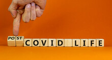 Symbol for a post-covid life. Businessman turns cubes and changes words 'covid life' to 'post-covid life'. Beautiful orange background. Medical, business and covid-19 pandemic concept, copy space.