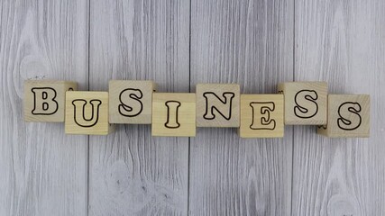 Fototapete - Wooden blocks with letters spelling - Business - in a conceptual image in an overhead view on grey wood planks with copyspace. Stop motion, top view