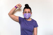 © AliciaFdez - Mujer joven levantando el puño. Lleva una camiseta morada y una mascarilla desechable con el símbolo de la mujer para protegerse del covid-19. Día Internacional de la Mujer 8 Marzo. Concepto feminismo