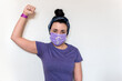 © AliciaFdez - Mujer joven levantando el puño. Lleva una mascarilla desechable con el símbolo de la mujer para protegerse del coronavirus. La chica viste una camiseta morada y un pañuelo. Día de la mujer, 8 Marzo