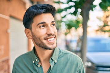 Young latin man smiling happy walking at the city.