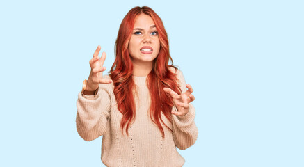 Poster - Young redhead woman wearing casual winter sweater shouting frustrated with rage, hands trying to strangle, yelling mad