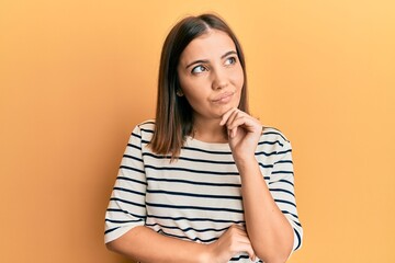 Sticker - Young beautiful woman wearing casual striped t shirt thinking concentrated about doubt with finger on chin and looking up wondering