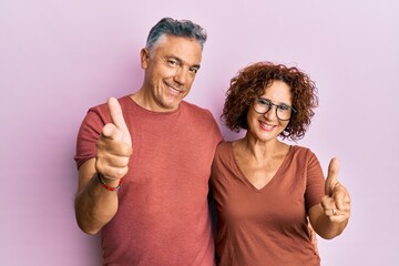 Poster - Beautiful middle age couple together wearing casual clothes pointing fingers to camera with happy and funny face. good energy and vibes.