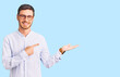 © Krakenimages.com - Handsome young man with bear wearing elegant business shirt and glasses amazed and smiling to the camera while presenting with hand and pointing with finger.