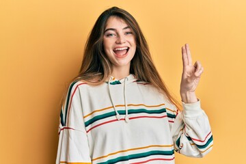 Young caucasian woman wearing casual clothes smiling looking to the camera showing fingers doing victory sign. number two.