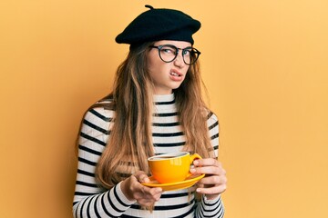 Sticker - Young caucasian woman wearing french style drinking a cup of coffee skeptic and nervous, frowning upset because of problem. negative person.