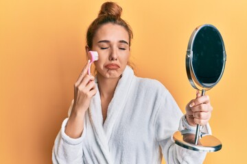 Wall Mural - Young blonde woman wearing robe holding makeup remover brush depressed and worry for distress, crying angry and afraid. sad expression.