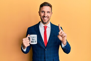 Sticker - Handsome business man with beard drinking from i am the boss coffee cup smiling with an idea or question pointing finger with happy face, number one