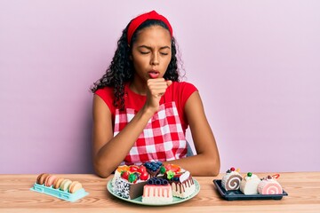 Poster - Young african american girl wearing baker uniform sitting on the table with sweets feeling unwell and coughing as symptom for cold or bronchitis. health care concept.