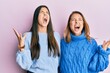 © Krakenimages.com - Hispanic family of mother and daughter wearing wool winter sweater crazy and mad shouting and yelling with aggressive expression and arms raised. frustration concept.