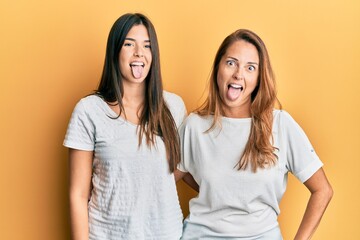 Poster - Hispanic family of mother and daughter wearing casual white tshirt sticking tongue out happy with funny expression. emotion concept.