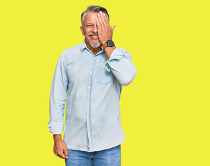 Sticker - Middle age grey-haired man wearing casual clothes covering one eye with hand, confident smile on face and surprise emotion.