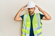 © Krakenimages.com - Handsome man with beard wearing safety helmet and reflective jacket with hand on head, headache because stress. suffering migraine.