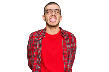 Hispanic young man wearing casual clothes sticking tongue out happy with funny expression. emotion concept.