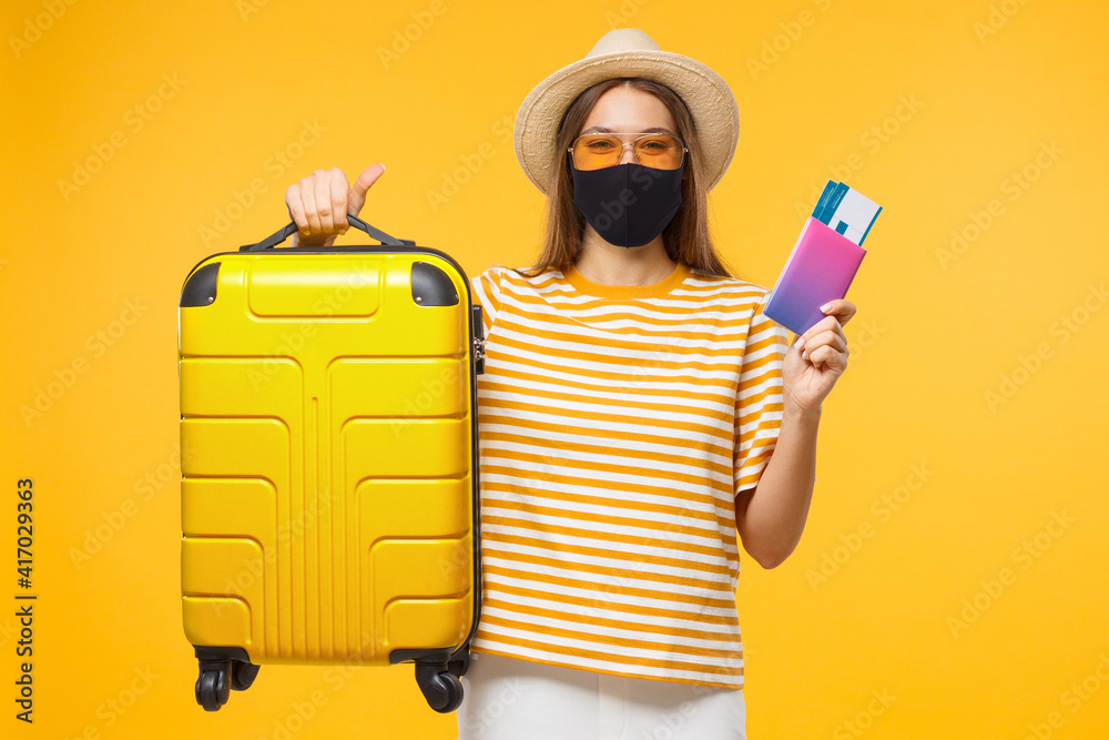 Immunity passport. Happy young woman tourist is ready to travel, holding suitcase and tickets to safe flight after end of coronavirus lockdown or having negative covid test - obrazy, fototapety, plakaty 