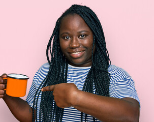 Poster - Young black woman with braids drinking a cup coffee smiling happy pointing with hand and finger