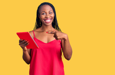 Poster - Young african american woman holding touchpad smiling happy pointing with hand and finger