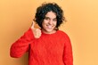 © Krakenimages.com - Young hispanic woman with curly hair wearing casual winter sweater doing happy thumbs up gesture with hand. approving expression looking at the camera showing success.