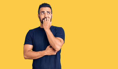 Poster - Young hispanic man wearing casual clothes looking stressed and nervous with hands on mouth biting nails. anxiety problem.