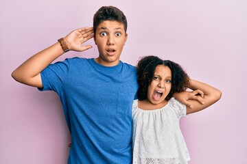 Wall Mural - Young hispanic family of brother and sister wearing casual clothes together crazy and scared with hands on head, afraid and surprised of shock with open mouth