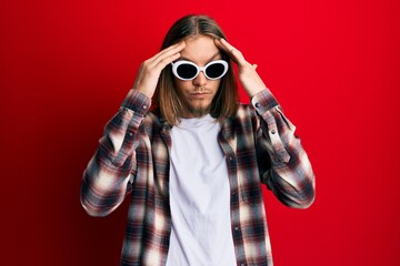 Wall Mural - Handsome caucasian man with long hair wearing hipster shirt wearing sunglasses with hand on head, headache because stress. suffering migraine.