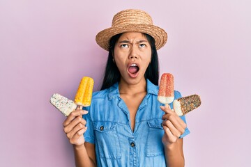 Poster - Young chinese woman wearing summer style holding ice cream angry and mad screaming frustrated and furious, shouting with anger looking up.