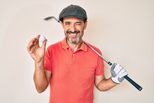 Middle Age Hispanic Man Holding Golf Club And Ball Winking Looking At The Camera With Sexy Expression, Cheerful And Happy Face.