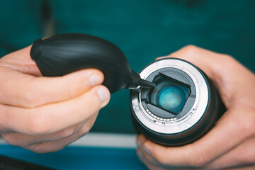 Close up of photographer hands cleaning camera lens with dust cleaner, air blower or vacuum pump. Photography equipment care