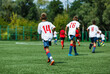© Natali - Young sport boys in white sportswear running and kicking a  ball on pitch. Soccer youth team plays football in summer. Activities for kids, training