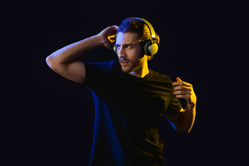 Canvas Print - Handsome young man listening to music on dark background