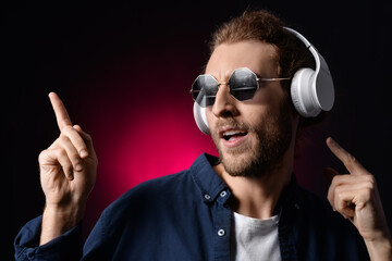 Sticker - Handsome young man listening to music on dark background